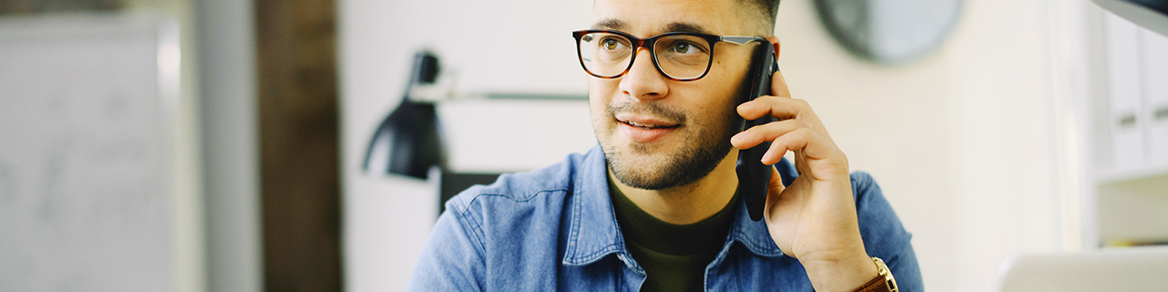 Man talking on smartphone sitting at desk