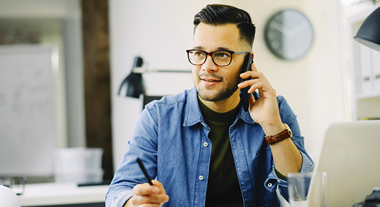 Man talking on smartphone sitting at desk