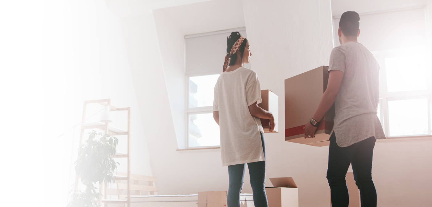 Couple in new home carrying boxes